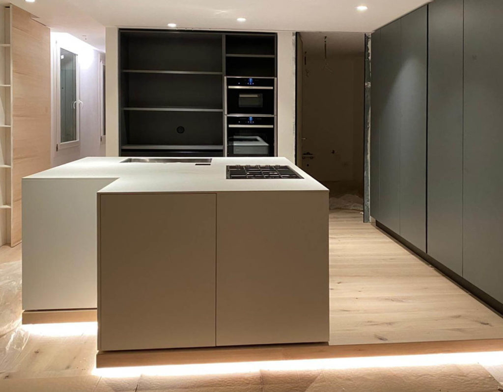 Residenza privata a Desenzano: Design ICM - Cucina con isola: l'anta opaca laccata bianco seta, abbinata al piano in Corian spessore 1.2, sviluppano un monolite operativo. Colonne laccate grigio opaco silice.